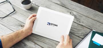 Osoba trzyma pudełko z napisem Optima na biurku