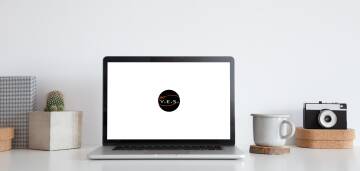 Laptop z logo na białym biurku, widok studyjny