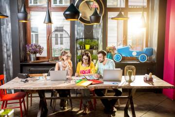 Rodzina przy stole w biurze coworkingowym, laptop i lampy